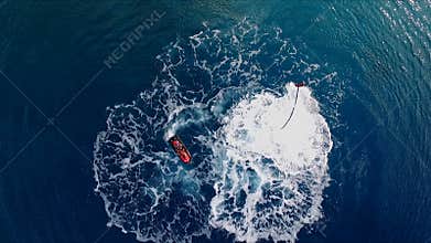 The man is having fun, flying over the water on a flyboard, under the pressure of water. Aerial video shooting, bird`s