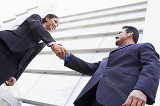 Business people shaking hands outside office