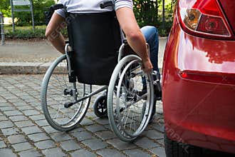Disabled man sitting on a wheelchair near his car