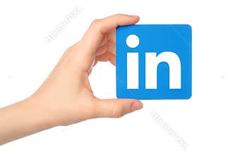 Hand holds Linkedin logo sign printed on paper on white background