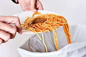 Young man throwing leftovers to the trash bin