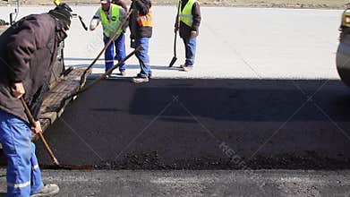 Tracked paver laying fresh asphalt pavement