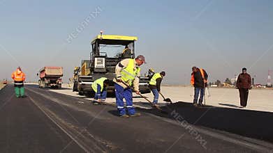 Construction workers leveling fresh asphalt pavement