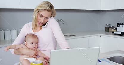 Mother calling while carrying her baby