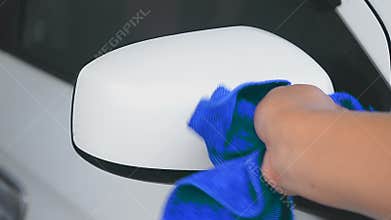 Hand of man using blue micro fiber fabric to clean car