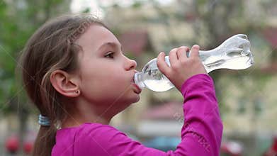 Child drinking water from bottle outdoor. Young girl with water bottle in hand