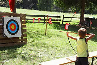 Blond hair kid playing archery during children summer games