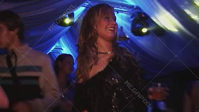 Young girl with glass in hands dance in nightclub. Spotlights. Smile. Cheering. Night party