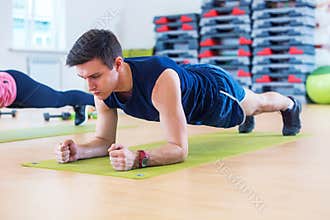 Fitness training athletic sporty man doing plank exercise in gym or yoga class exercising workout