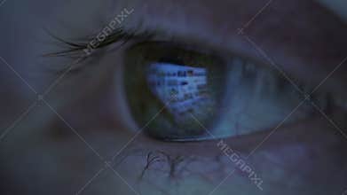 Close-up of woman eyes looking at monitor, working with computer, laptop. Monitor light is reflected in brown eyes.