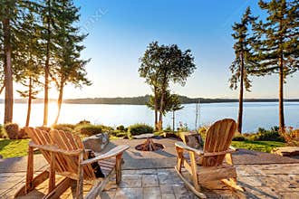 Back yard of waterfront house with adirondack chairs and fire pit