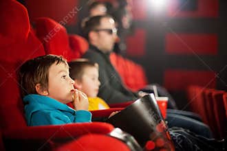 Father and two children, boys, watching cartoon movie in the cinema
