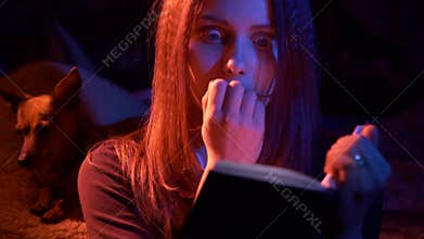 Teen girl reading scary book at night
