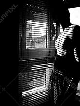 Self portrait of male model shirtless and looking out a window