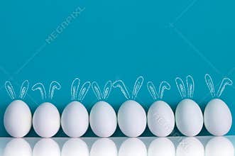 Easter eggs painted with rabbits ears and ballooons on the blue background