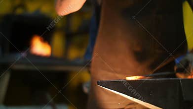 Blacksmith Hitting Hot Metal with a Hammer on an Anvil inside His Workshop in Slow Motion