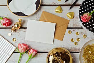 Greeting card mock up template with rose flowers and chocolates on wooden background. View from above