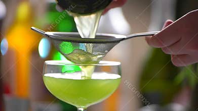 Cocktail slowly pours through sieve.