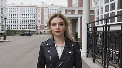 Beautiful young woman walking on the street. Blonde confident gait moves the camera. City motif, an elite residential