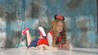 Little girl with long braids in a red jacket. Posing in the studio,