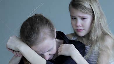Sad daughter hugging his mother at home.