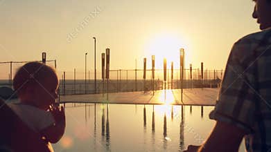 Happy family with three children admiring the sunset reflected in the surface of the pool