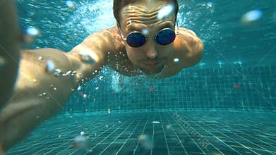 A young white handsome male doing an underwater selfie on an action camera. Portrait of a young man with glasses taking