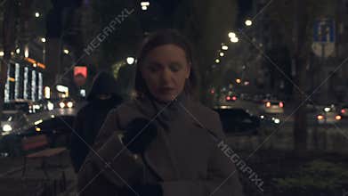 Dangerous criminal following young woman walking on night city street, bandit