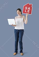 Woman holding a house sale icon and a laptop