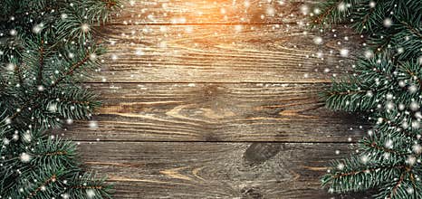 Old wood background with fir branches. Space for a greeting message. Christmas card. Top view. Effect of light and snowflakes