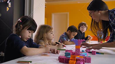Cute kids drawing with teacher at preschool class
