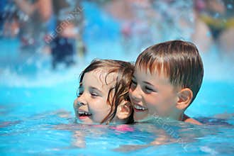Smiling boy and girl swimming in pool in aquapark