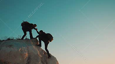 Teamwork friendship hiking help each other trust assistance silhouette in mountains. Backpacker helps to his friend to