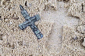 Footprint in the sand from a large cross lying next to a small
