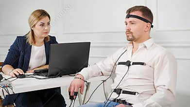 Polygraph technician reads questions from a laptop. man connected to the lie detector circuit