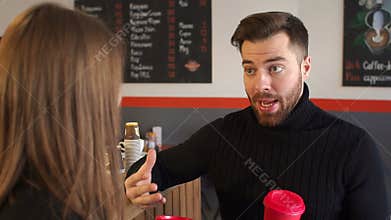 Close-up of a man with a Cup of coffee talking to his girlfriend in coffee shop.