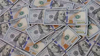 US 100 dollar bills being thrown on table full of dollar bills