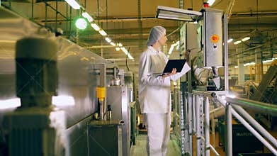 One person works with factory equipment in a food production facility.