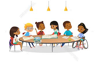 Smiling disabled girl in wheelchair and her school friends sitting around round table, reading books and talk to each