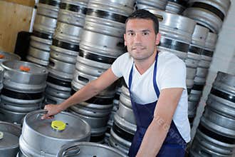 Worker with beer barrels at brewery