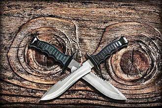 Tactical Combat Hunting Survival Bowie Knives With Crossed Blades On Grunge Vignetted Old Knotted Pinewood Grunge Background