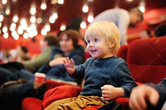 Cute toddler boy watching cartoon movie in the cinema