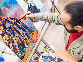 Male Artist Working On Painting In Bright Daylight Studio