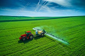 Aerial view of farming tractor plowing and spraying on field