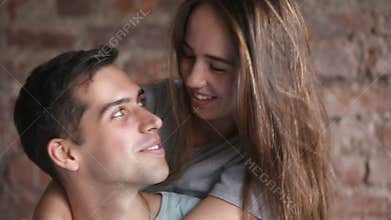 Young laughing couple hugging, having fun together, looking at camera
