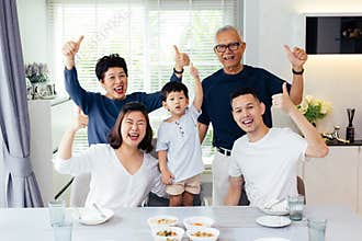 Extended Asian family of three generations having a meal together and showing thumbs up at home with happiness