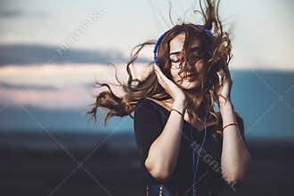 Portrait of a beautiful girl in headphones listening to music on nature