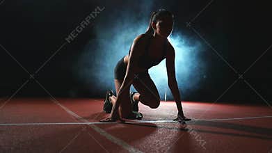 Athlete woman in black shorts and a t-shirt in sneakers are in the running pads on the track of the sports complex and
