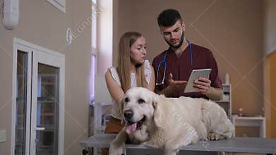 Vet talking to pet owner with tablet pc at clinic