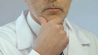 Middle aged doctor solving problem and making decision with hand on his chin